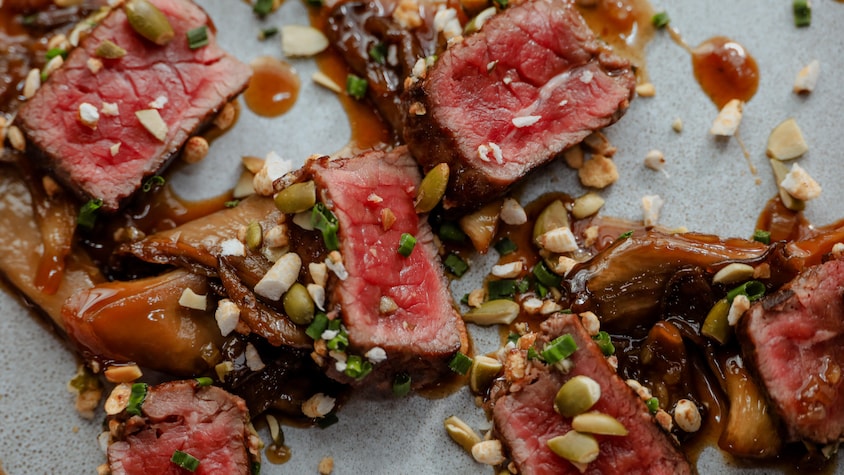 De fines lanières de bison en tataki, nappées de sauce à l'érable et garnies d'un mélange de noix et de fines herbes.