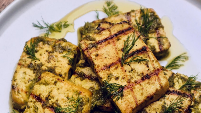 Des tranches de tofu grillé garnies d'huile d'olive et d'aneth frais.