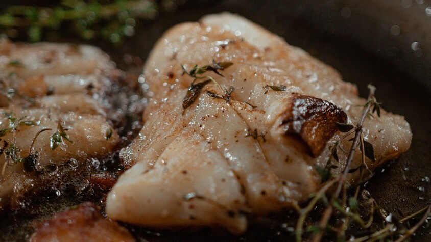 Des filets de turbot se faisant chauffer dans une poêle. 