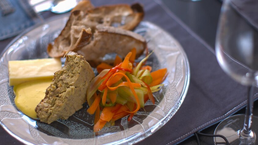 Un morceau de végé-pâté dans une assiette accompagné de légumes, de croûtons et d'une sauce jaune.