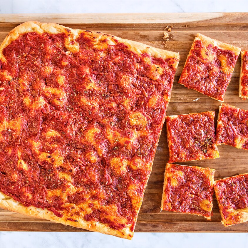 Une pizza froide sur une planche à découper avec certains morceaux de coupés.