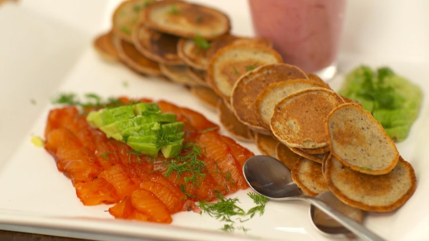 Des blinis et des tranches de saumon gravlax sur une grande assiette.