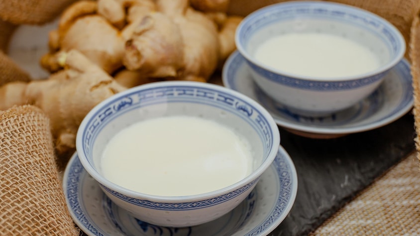 Deux bols avec du pouding au lait et au gingembre sont disposés sur une table.