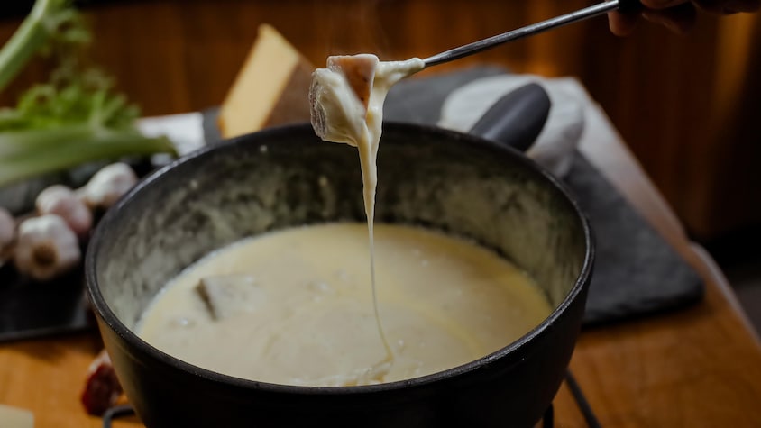 Une bouchée de pain dans un plat de fondue au fromage.