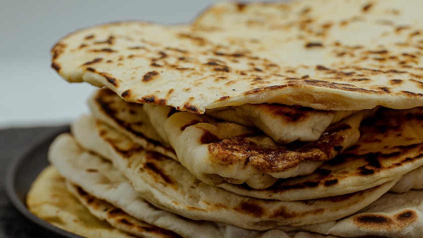 Une dizaine de pains pitas sont empilés dans une assiette.