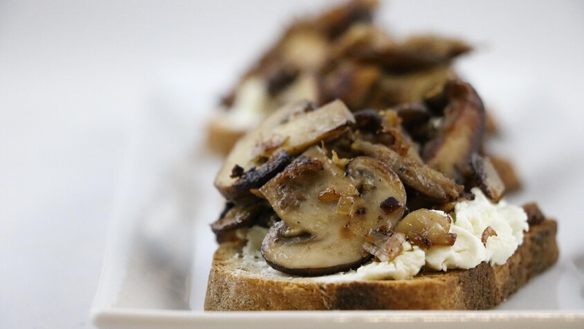 Des champignons sont déposés sur une tranche de pain.