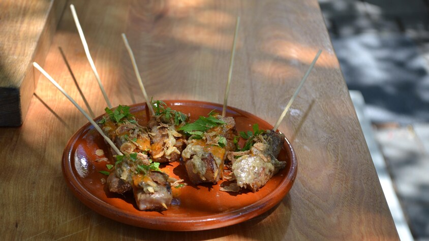 Cinq brochettes sont dans une assiette sur la table.