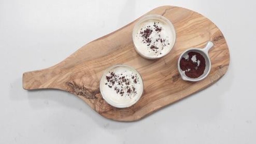 Deux bols de café sont sur une planche de bois.
