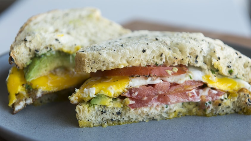 Dans un pain moelleux se trouvent de l'avocat, un œuf coulant et de la tomate.