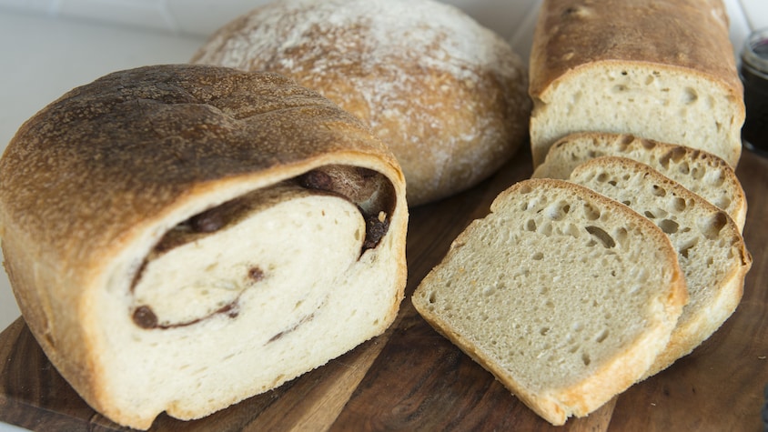 Un pain cannelle raisins, une miche ronde et un pain carré tranché.
