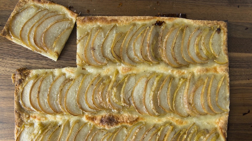 De la pâte recouverte de fines tranches de poire et dorée au four.