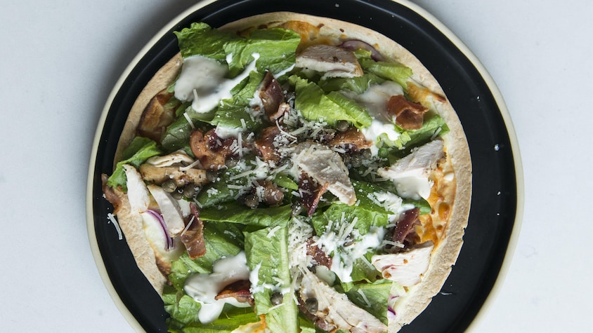 Une salade césar au poulet sur une croute de pizza.