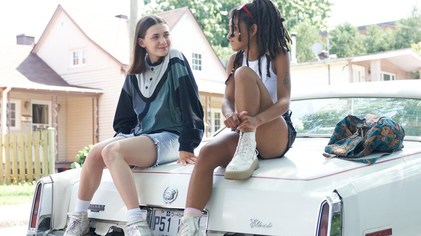 Les productions passez go Les deux filles assises sur la voiture.