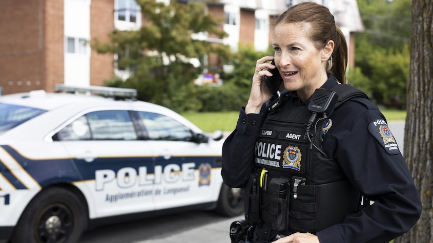 Une policière, qui porte son uniforme, parle au téléphone. 