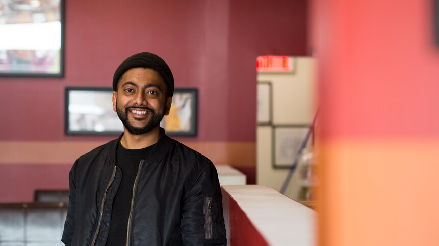 Aakash Patel sourit pour la caméra dans son restaurant.