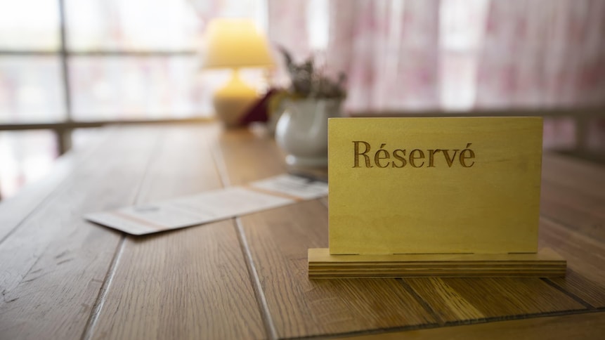 Petit écriteau sur lequel est écrit « Réservé » sur une table de restaurant.