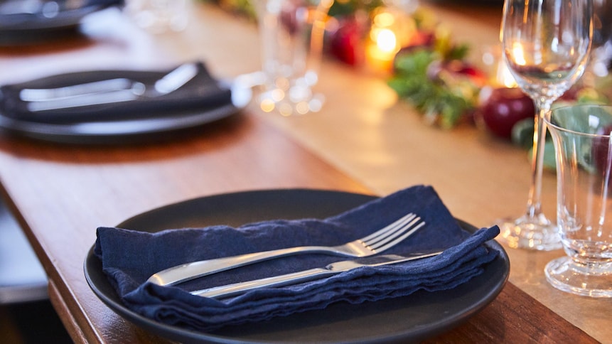Assiette foncée avec serviette en tissu bleu et couvert sur le dessus.