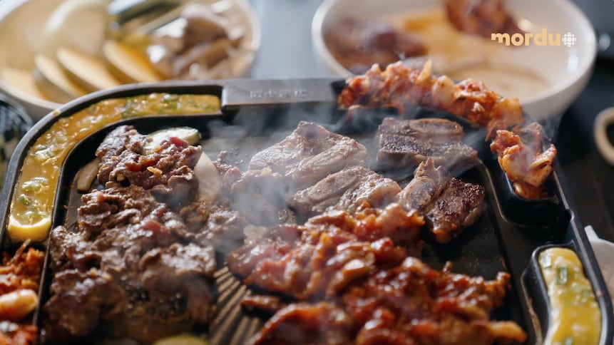 Un BBQ coréen sur lequel cuit plusieurs morceaux de viande.