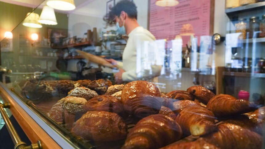 Des croissants sur un comptoir, avec un employé en arrière-plan.