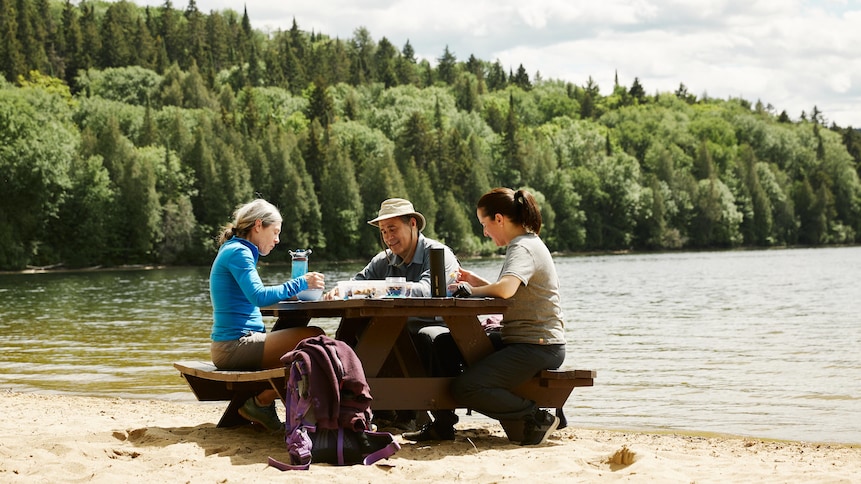 Geneviève mange une salade de couscous dans la réserve faunique Mastigouche avec des invités. 