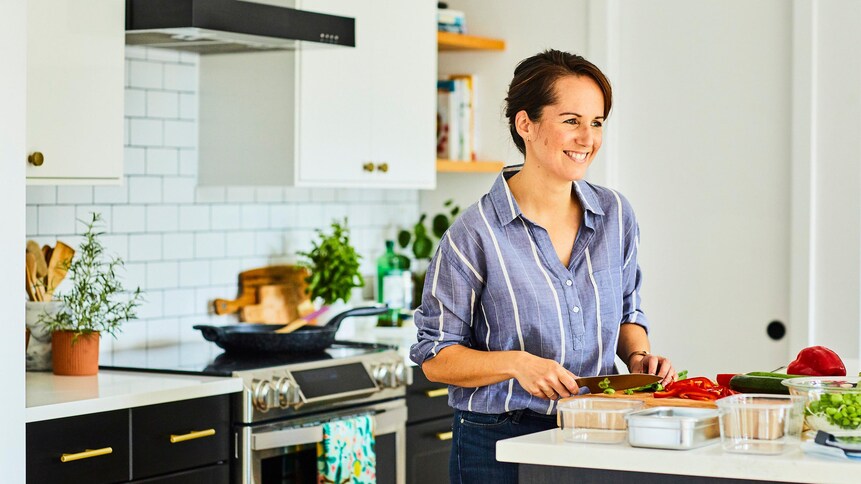 Geneviève O'Gleman qui coupe des légumes sur une planche à découper.