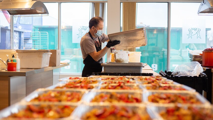 Une personne est en train de remplir des contenants de nourriture prête à manger.
