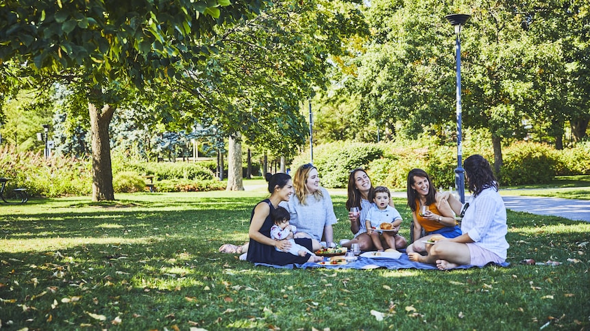 Un groupe d’amis font un pique-nique dans un parc. 