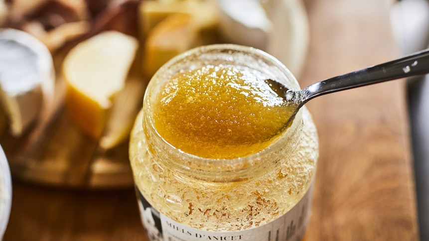 Une cuillère dans un pot de miel qui a commencé à se cristalliser.