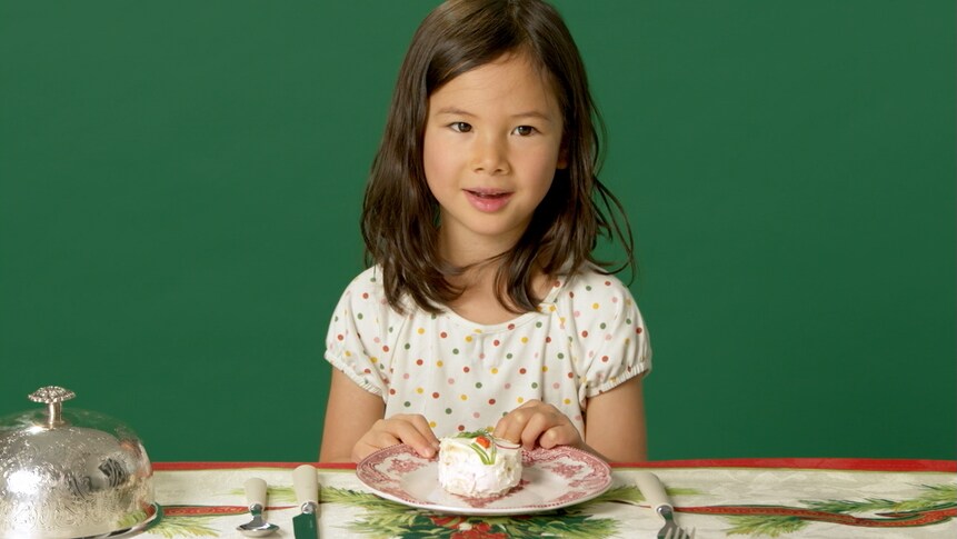 Une petite fille devant une assiette contenant une portion de pain sandwich.