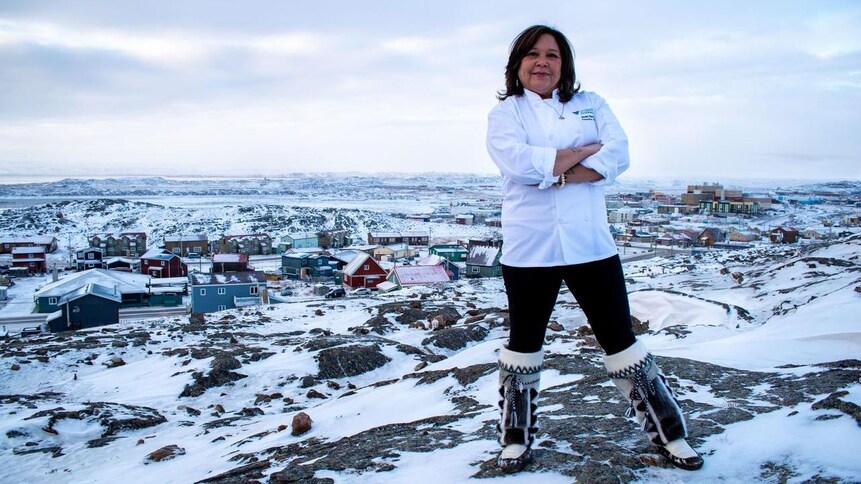 La chef pose devant une ville enneigée du Nord canadien.