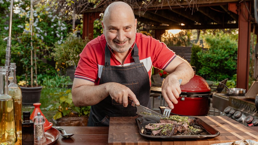 Le chef Marc Maulà coupe son steak dans une cuisine extérieure.