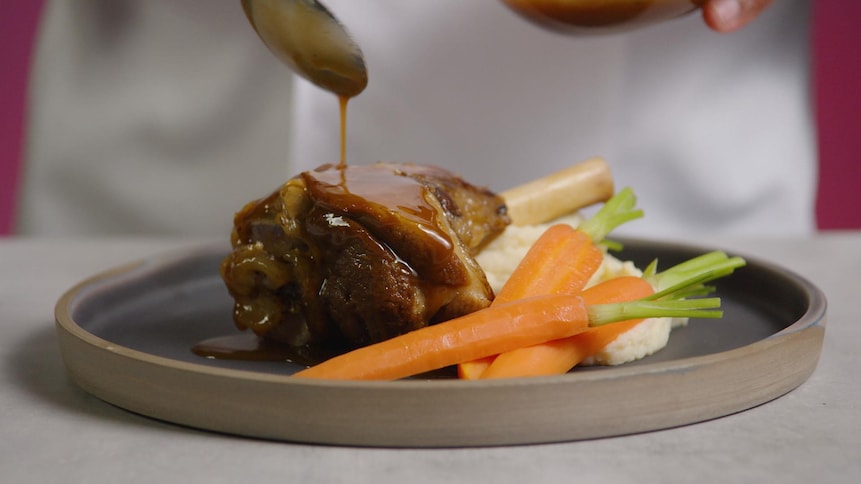 De la viande et des carottes dans une assiette avec un coulis d'une sauce brune. 