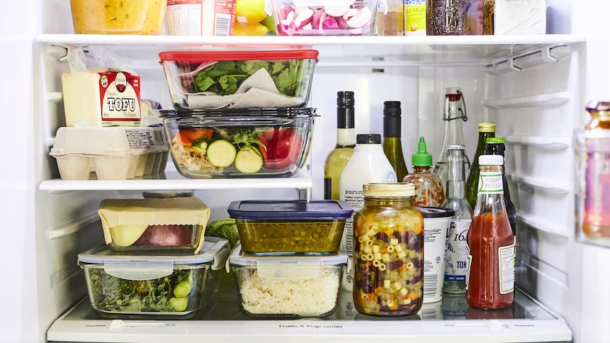 Sur l'étage du milieu d'un réfrigérateur, des ingrédients sont bien rangés et alignés. Les aliments solides sont placés à gauche et les aliments liquides sont placés à droite.