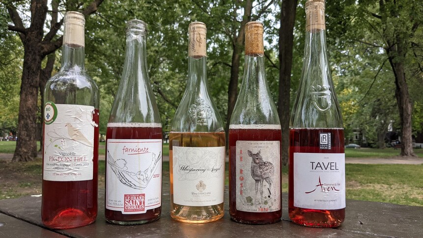 Cinq bouteille de vin rosé sur une table.