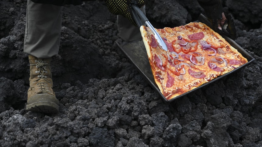 Une personne regarde la cuisson d'une pizza déposée sur une coulée de lave.