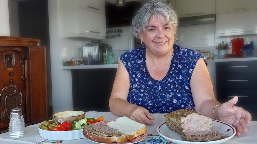 Une femme dans sa cuisine avec un pain de viande.