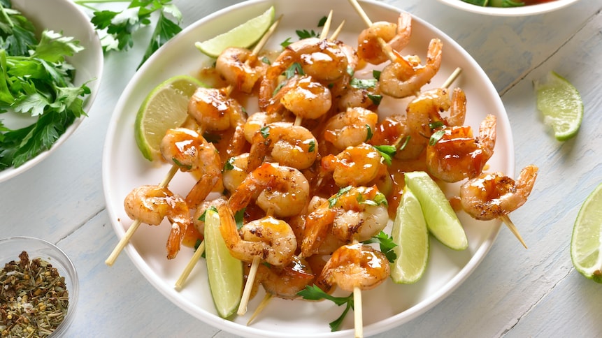 Plusieurs brochettes de crevettes recouvertes de marinade mexicaine.