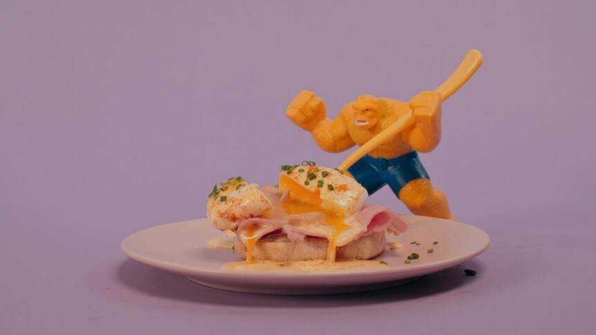 Un œuf mollet est posé sur une tranche de jambon et de pain. 