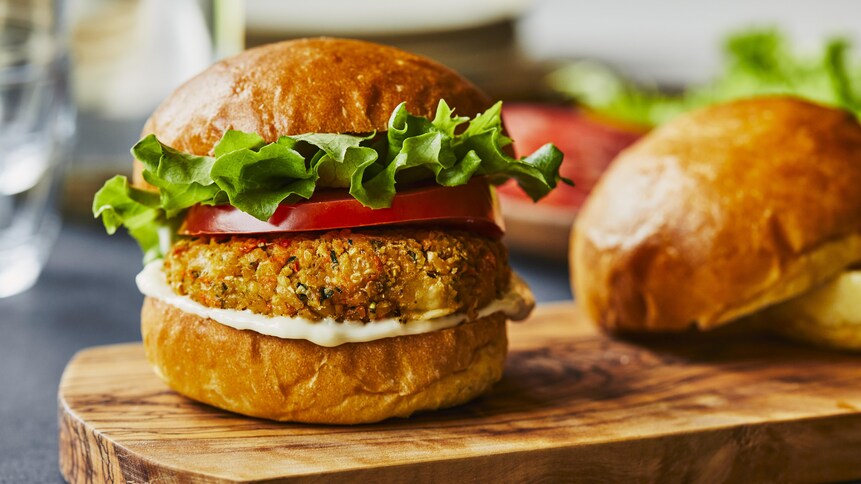 Un végé-burger extra légumes sur une planche à découper en bois. 