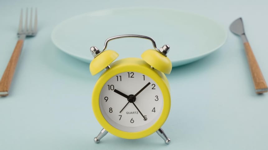 Une horloge jaune devant une assiette vide.