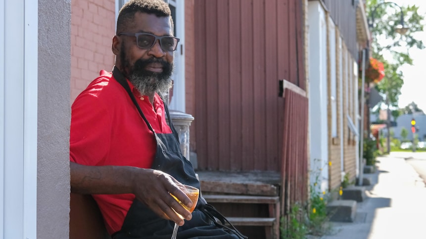 Un homme assis sur un banc regarde la caméra. 