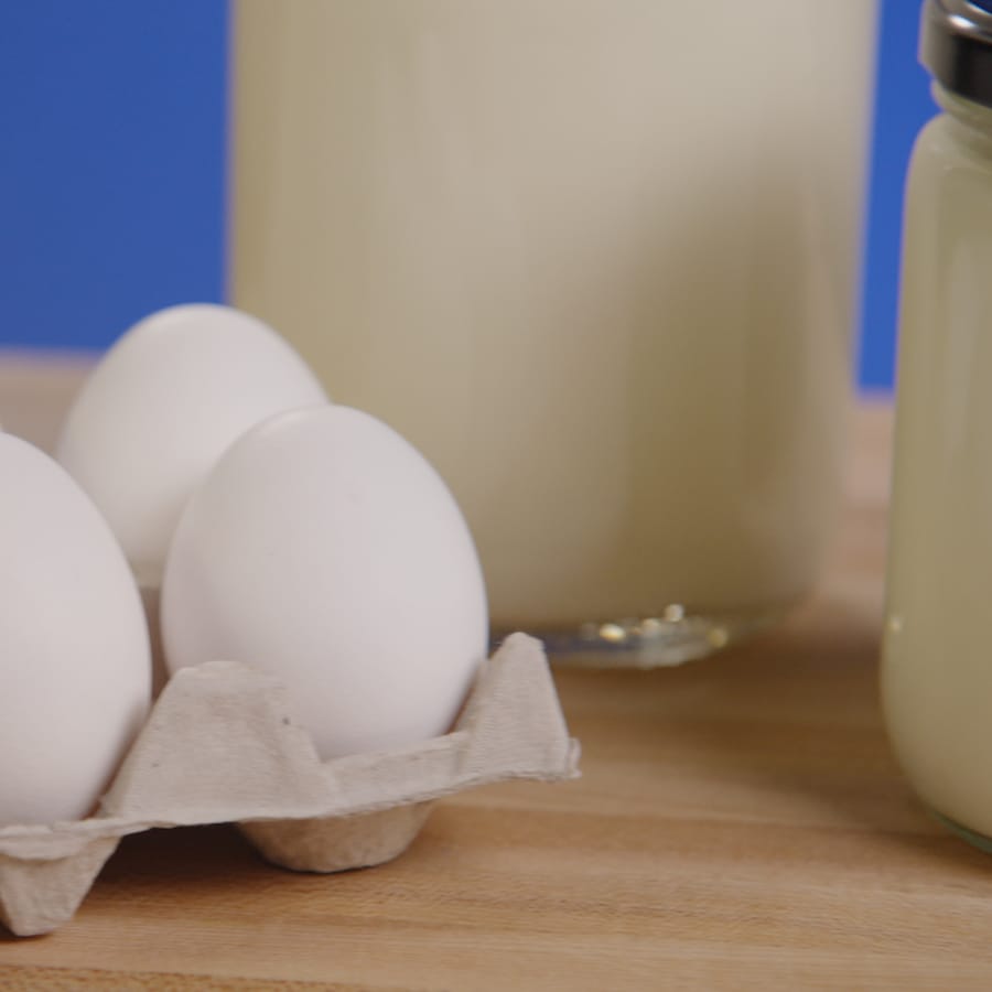 Des œufs et des petits pots de lait sont posés sur un ilot de cuisine. 