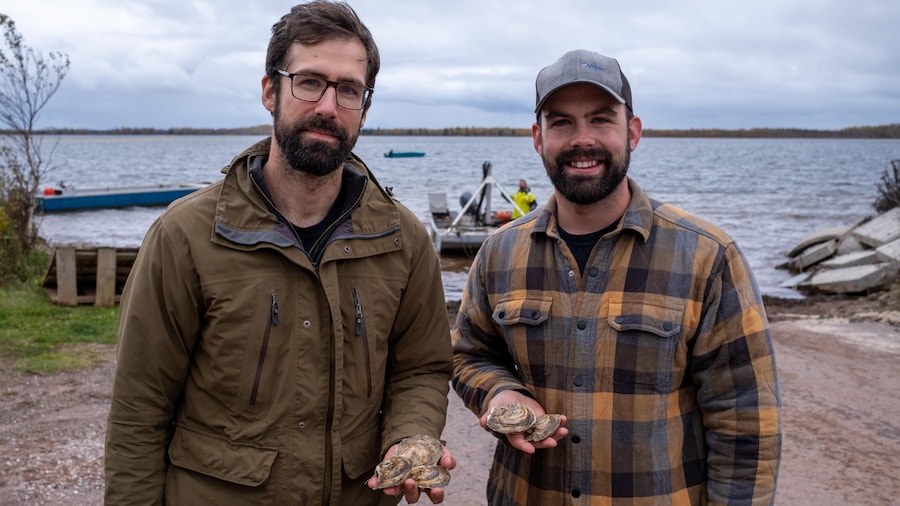 Deux hommes tenant des huîtres dans leur main.