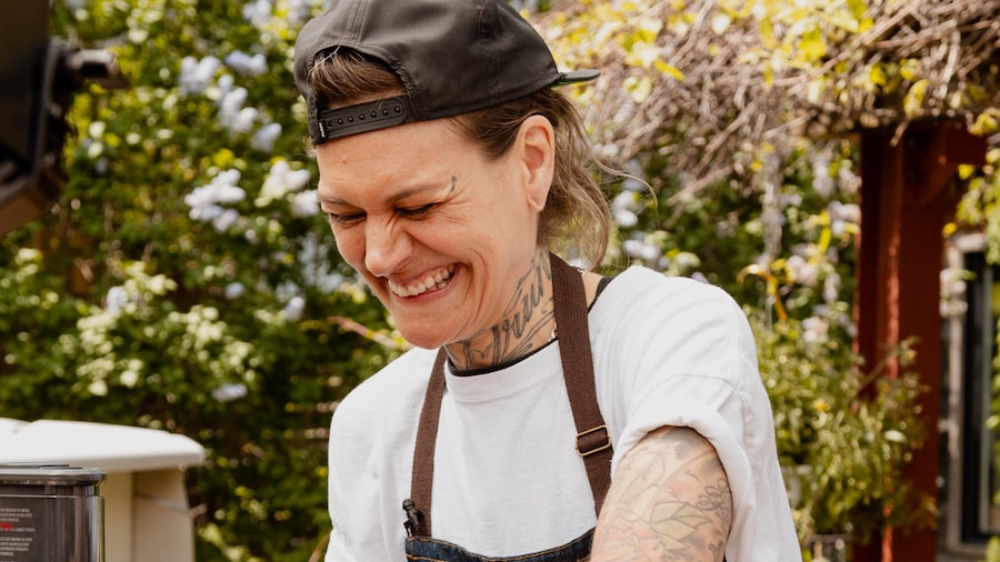 MJ Guertin dans une cuisine extérieure en train de cuisiner du satay de seitan.