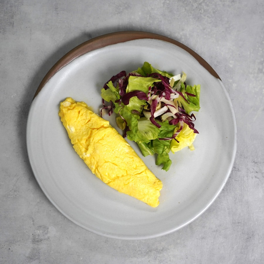 Une omelette dans une assiette avec une salade.