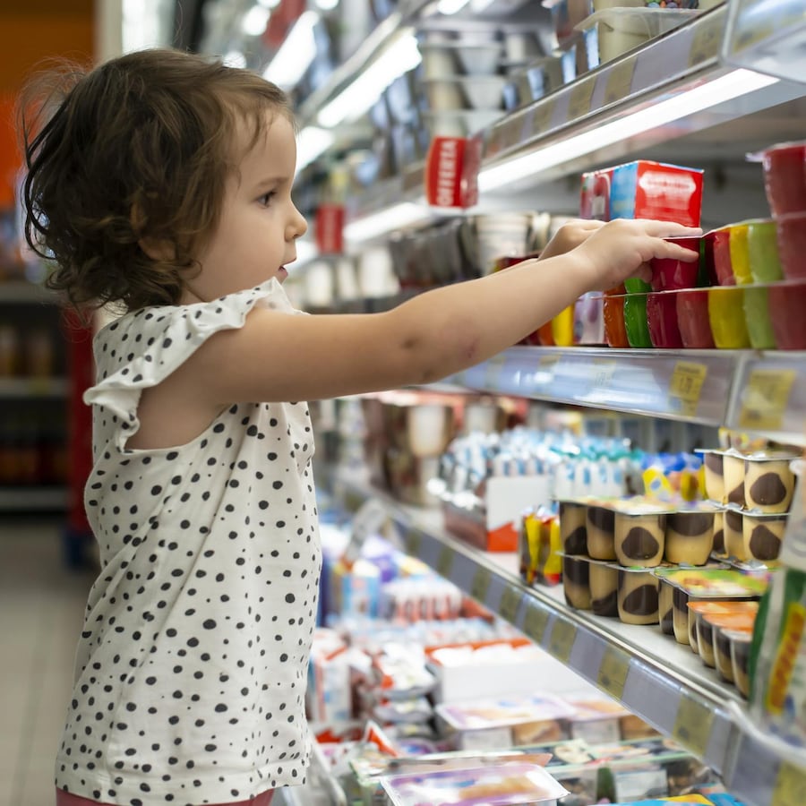 Une petite fille est attirée par l'emballage coloré d'un produit au supermarché.