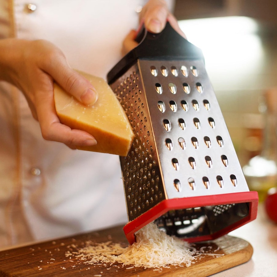 Un chef râpe un morceau de fromage.