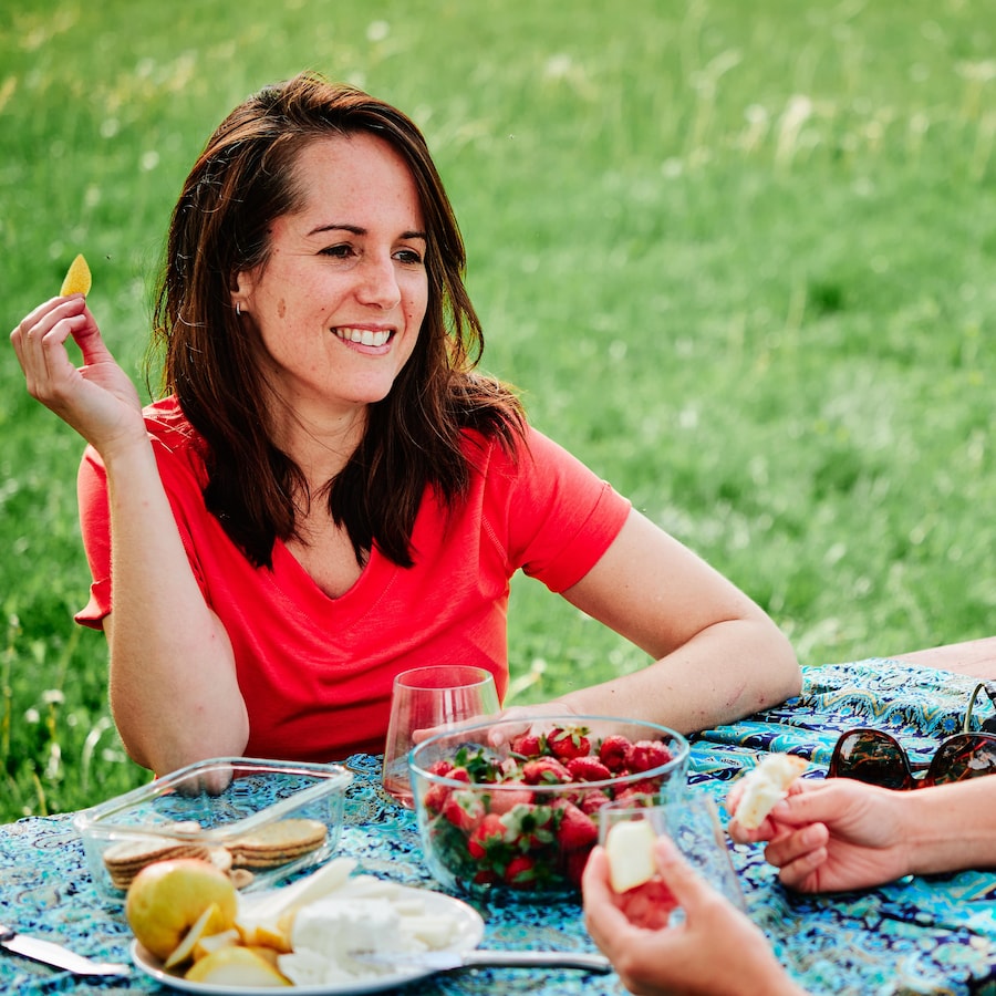 La nutritionniste Geneviève O'Gleman est assise sur une table à pique-nique avec un morceau de poire à la main.