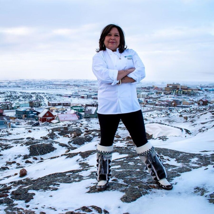 La chef pose devant une ville enneigée du Nord canadien.