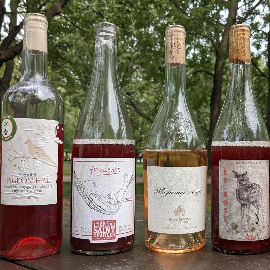 Cinq bouteille de vin rosé sur une table.